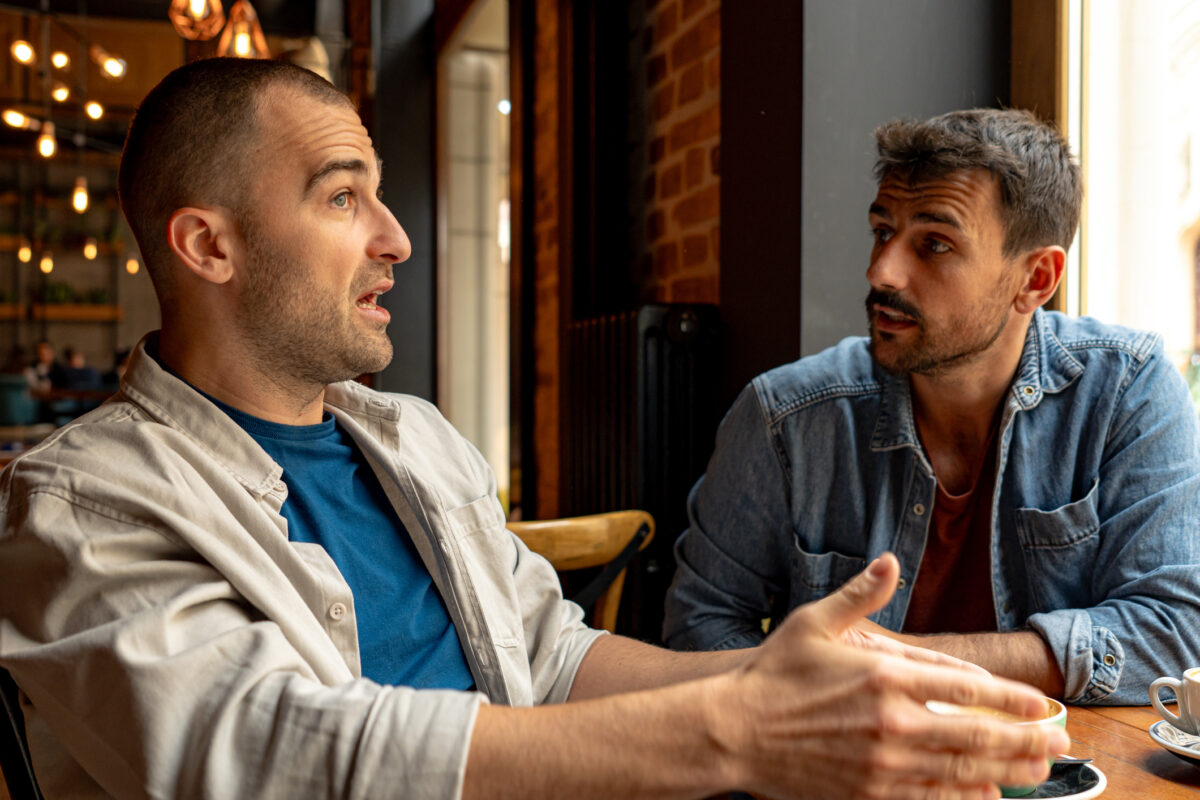 Two men discussing and gesturing in a coffee shop